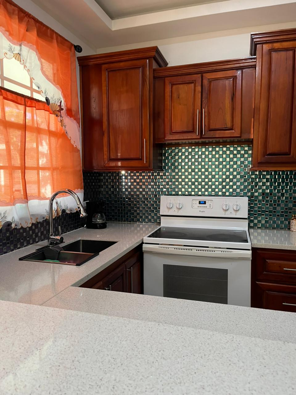 Kitchen with quartz counter, mosaic backsplash and full-size range